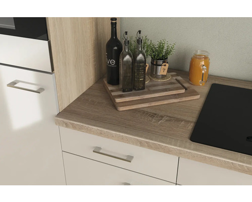 Küchenarbeitsplatte mit Spüle, Schneidebrettern, Ölflaschen, Kräutern und Getränk