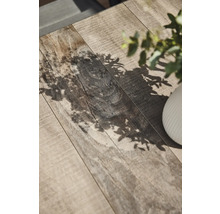 Nahaufnahme einer Tischplatte mit Holzstruktur und Pflanzenschatten