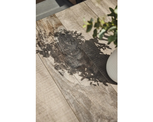 Nahaufnahme einer Tischplatte mit Holzstruktur und Pflanzenschatten