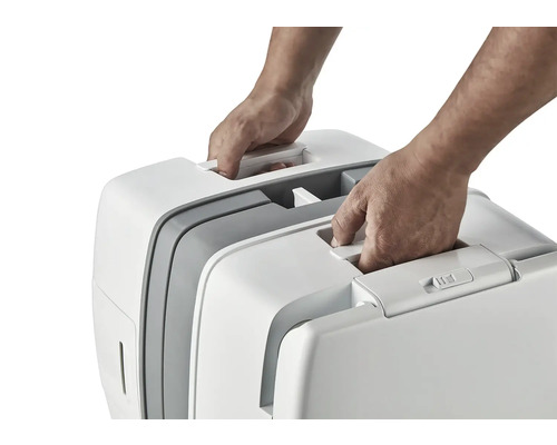 Zwei Hände heben eine tragbare Katzentoilette am Griff an.