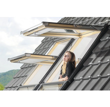 Frau schaut aus geöffnetem Dachfenster mit grauen Dachziegeln