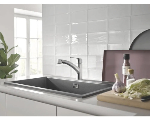 Küchenszene mit Spüle, Armatur und Lebensmitteln auf einer Arbeitsplatte.