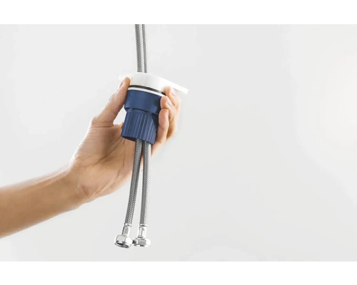 Eine Hand hält einen Wasserhahn-Schnellverbinder mit zwei flexiblen Schläuchen.