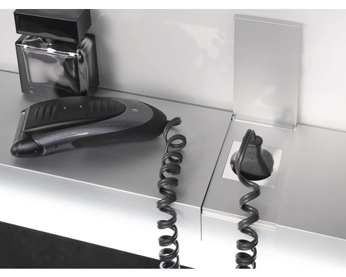 Elektrischer Rasierer, Parfüm und Steckdose mit Spiralkabel auf einer Ablage