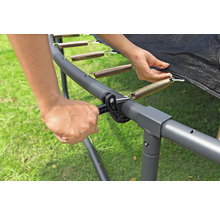 Person befestigt eine Feder am Trampolinrahmen mit einem Spannwerkzeug