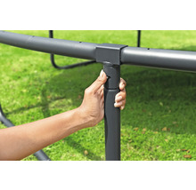 Eine Hand befestigt ein Trampolinbein am Rahmen.