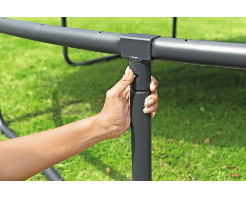 Eine Hand befestigt ein Trampolinbein am Rahmen.