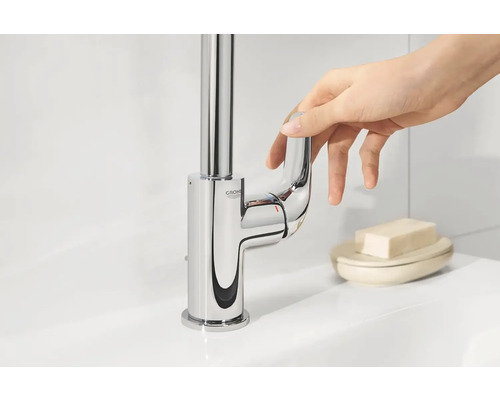 Glänzende Waschtischarmatur mit Einhebelmischer und Grohe Logo wird von einer Hand bedient.