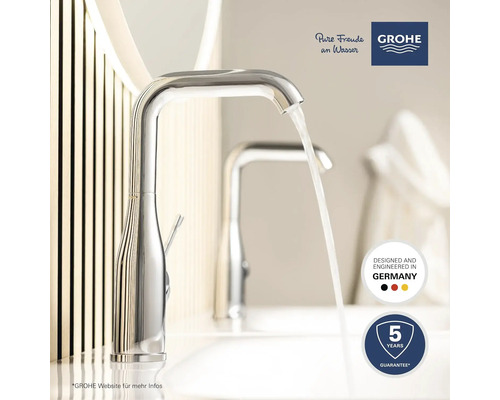 Nahaufnahme einer glänzenden Armatur mit fließendem Wasser im Badezimmer. Grohe Logo. Fünf Jahre Garantie. Hergestellt in Deutschland.