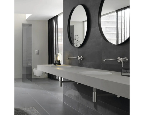 Modernes Badezimmer mit Doppelwaschbecken, runden Spiegeln und grauer Fliesenwand.