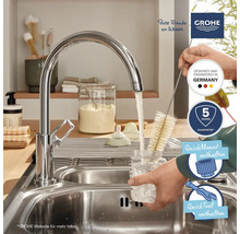Küchenszene mit Grohe Armatur, Flaschenbürste, Spülbecken und Logos.