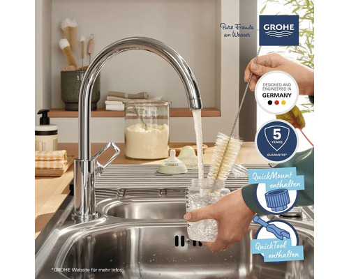 Küchenszene mit Grohe Armatur, Flaschenbürste, Spülbecken und Logos.