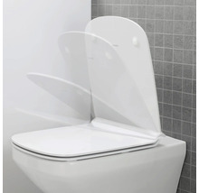Weisse Toilette mit offenem Toilettendeckel vor grauer Wand