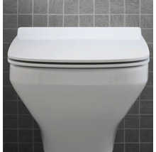 Nahaufnahme einer weißen Toilette mit geschlossenem Deckel vor einer grauen Wand