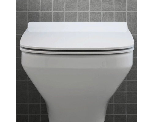Nahaufnahme einer weißen Toilette mit geschlossenem Deckel vor einer grauen Wand