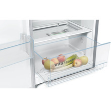 Innenraum eines Kühlschranks mit einer transparenten Gemüseschublade gefüllt mit Äpfeln und Lauch