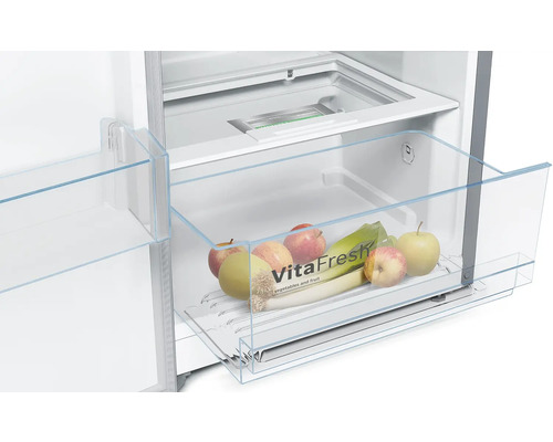 Innenraum eines Kühlschranks mit einer transparenten Gemüseschublade gefüllt mit Äpfeln und Lauch