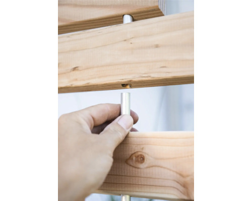 Detailansicht einer Holzkonstruktion mit einer Hand, die einen Metallstift hält