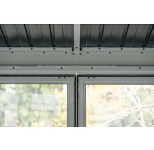 Detailansicht des Dachs und der Fenster eines Gartenhauses.