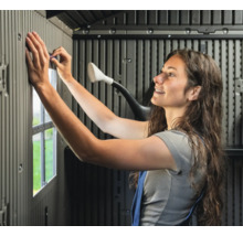 Frau montiert ein Gartenhaus aus Kunststoff