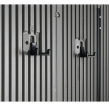 Zwei schwarze Gerätehalter an einer grau gerillten Wand