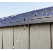 Wasser fließt vom Dach eines Gartenhauses.