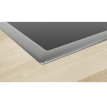 Detailansicht eines Kochfelds mit Edelstahlrahmen auf einer Arbeitsplatte