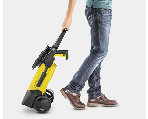 Eine Person zieht einen gelben Hochdruckreiniger.