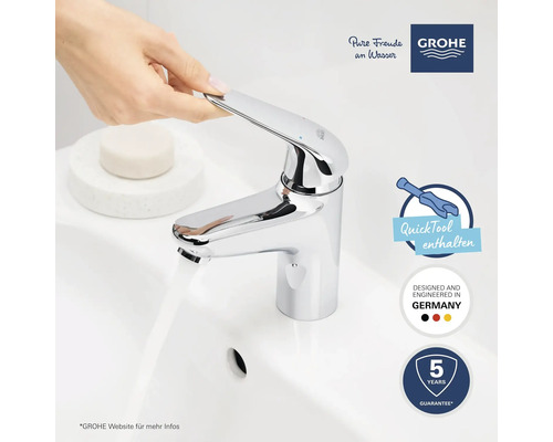 Glänzender Wasserhahn auf einem Waschbecken mit dem Grohe Logo, dem Quicktool enthalten Symbol und dem Designed and Engineered in Germany Symbol, sowie 5 Jahre Garantie Symbol.