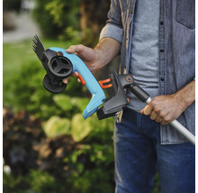 Person hält Akku-Gras- und Strauchschere mit Teleskopstiel