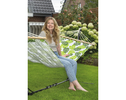 Frau entspannt in Hängematte mit Blattmuster im Garten