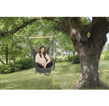 Frau sitzt in einer Hängematte im Garten unter einem Baum