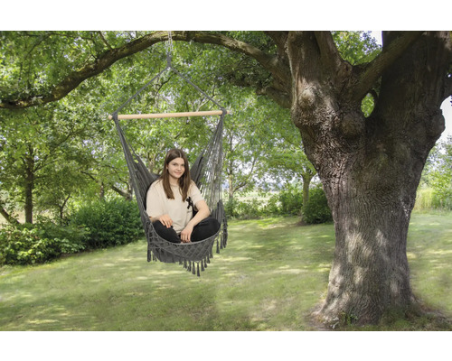Frau sitzt in einer Hängematte im Garten unter einem Baum