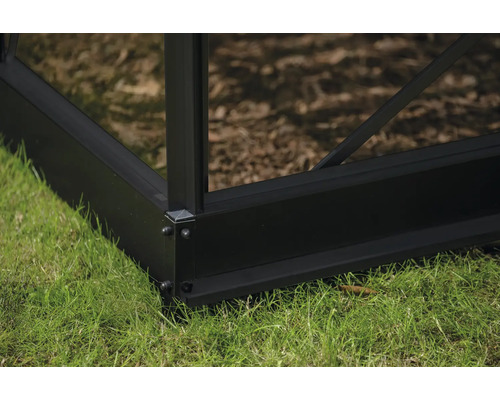 Detailaufnahme einer Gewächshaus-Ecke aus Metall auf Rasen.