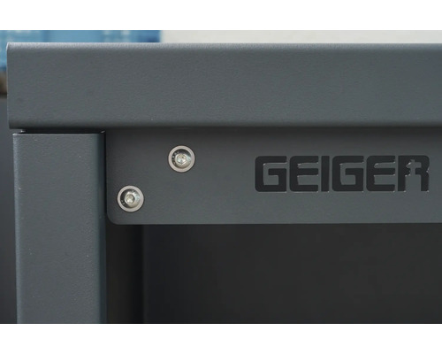 Detailansicht eines grauen Geiger Schranks mit Schrauben und dem Geiger Logo.