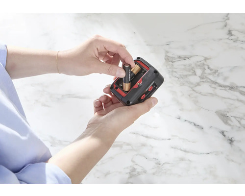 Person legt Batterien in ein elektronisches Gerät ein