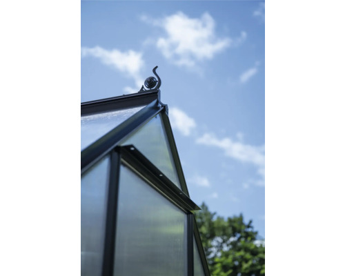 Detailansicht eines Gewächshauses mit dekorativer Dachspitze vor blauem Himmel