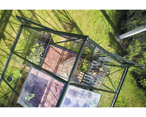 Draufsicht auf ein Gewächshaus mit Pflanzen und Gartenwerkzeugen auf einem Rasen