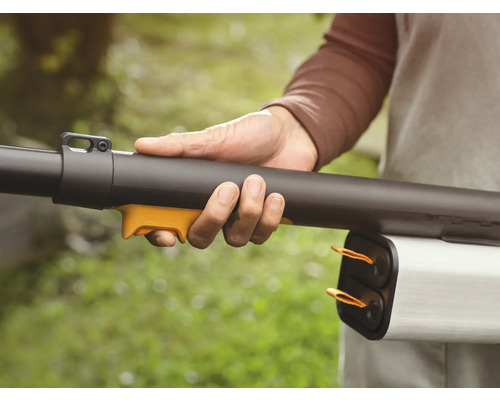 Eine Person hält einen Laubbläser in der Hand.