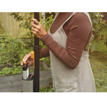 Eine Person setzt einen Akku in ein Gartengerät ein.