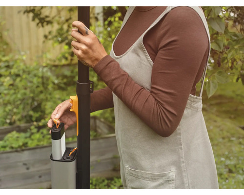 Eine Person setzt einen Akku in ein Gartengerät ein.