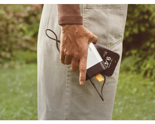 Eine Person hält ein Mobiltelefon und eine Powerbank.