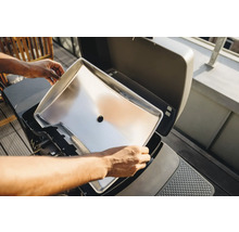 Edelstahl Grillwanne wird in einen Grill eingesetzt.