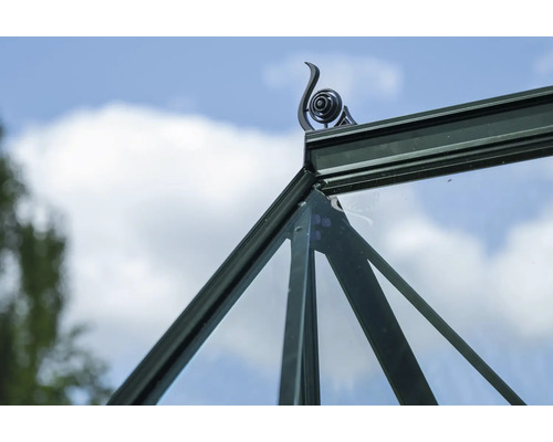 Detailaufnahme eines Gewächshauses mit dekorativem Dachaufsatz vor blauem Himmel