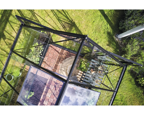 Draufsicht eines Gewächshauses mit Pflanzen und Gartengeräten auf Rasenfläche