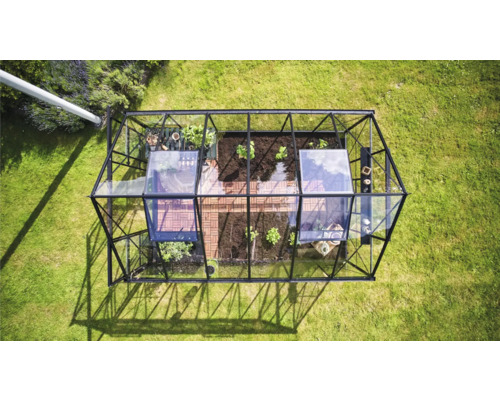 Draufsicht eines Gewächshauses aus Glas und Metall im Garten.