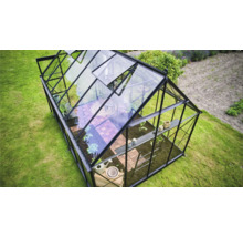 Gewächshaus mit Pflanzen und Gartenwerkzeugen im Garten