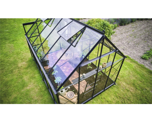 Gewächshaus mit Pflanzen und Gartenwerkzeugen im Garten