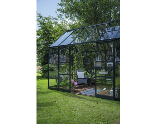 Gewächshaus mit Pflanzen, Stuhl und Gartenzubehör im Garten