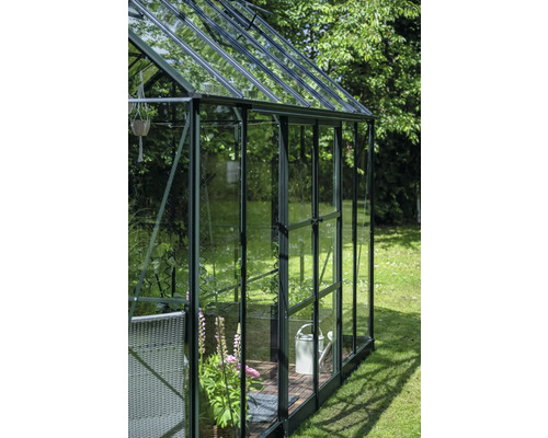 Gewächshaus mit Pflanzen und Gartenzubehör im Garten